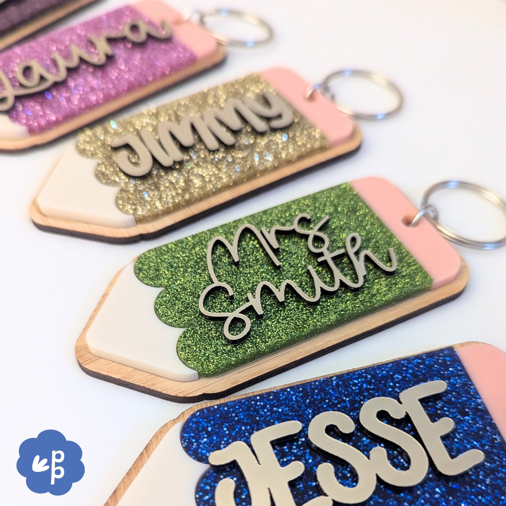 Close up of personalised glitter acrylic keyrings with layered name lettering and bamboo backing in vibrant colours