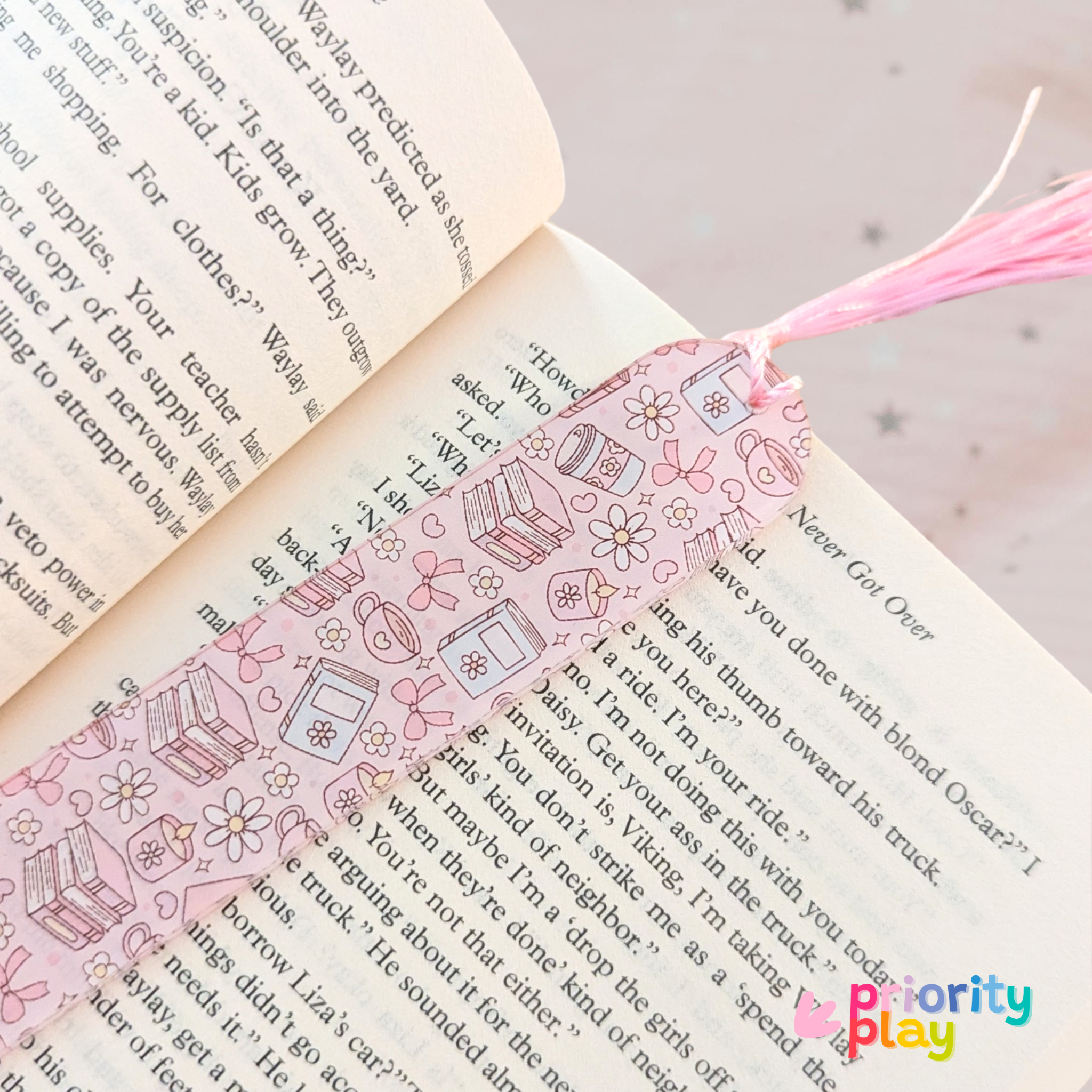 Pink pastel acrylic bookmark with pink tassel placed inside an open book
