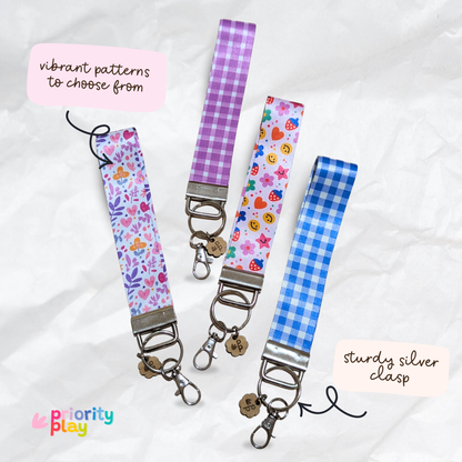 Handmade wristlet keychains with purple floral, heart, and blue gingham patterns, durable silver clasp key fobs for teachers.