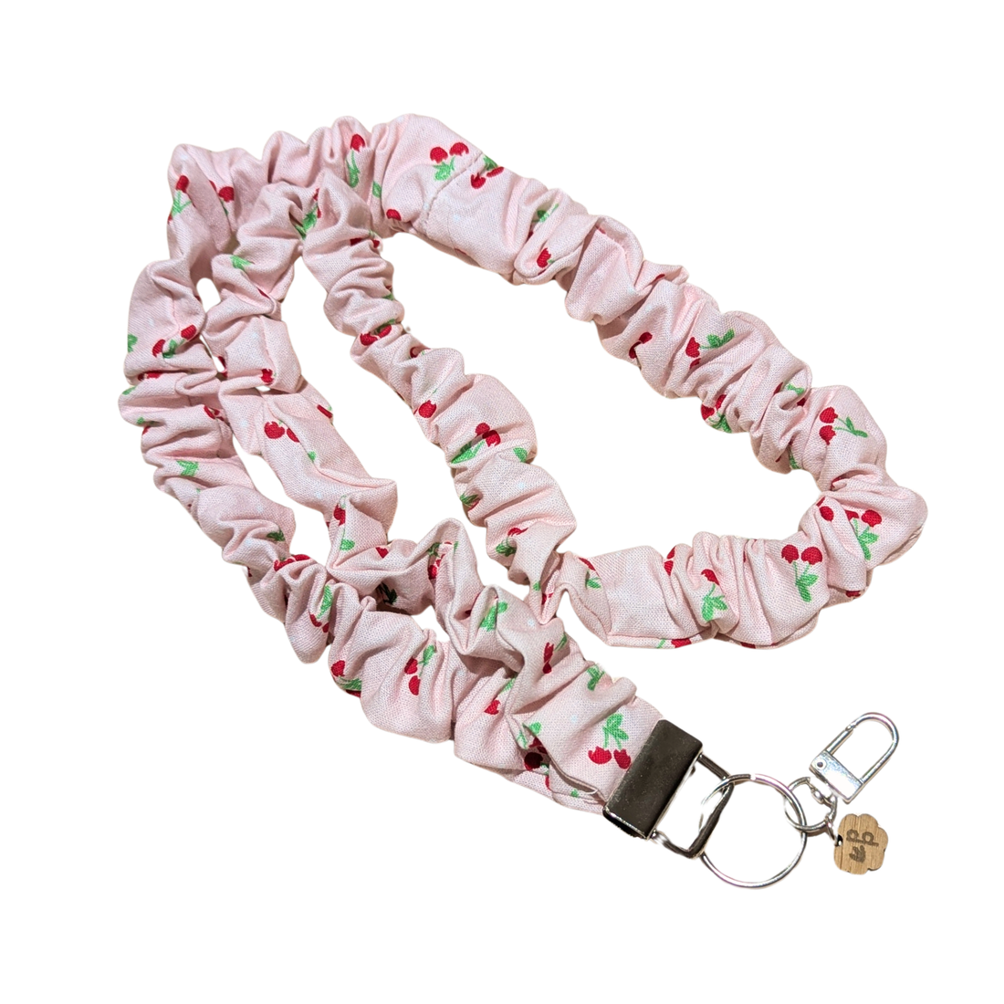 Pink scrunchie lanyard with cherry pattern and keychain on a white background
