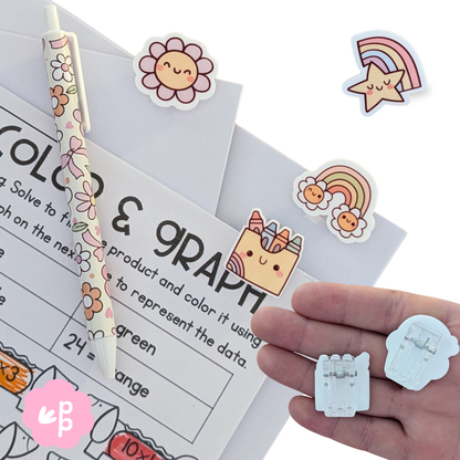 Cute acrylic stationery clips featuring smiling flowers, rainbows, and stars holding student worksheets – fun classroom accessories from Priority Play.