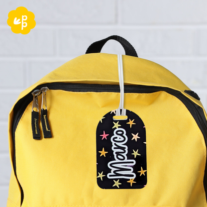 Custom name bag tag with star pattern attached to yellow backpack, personalised kids luggage tag by Priority Play