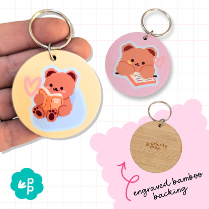 Cute bear keyring with reading and journaling bear design, featuring pastel colors and engraved bamboo backing by Priority Play