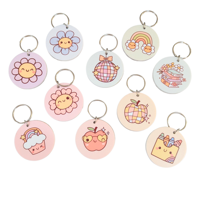 Cute round bamboo keyrings with pastel designs including flowers, rainbows, apples, and disco balls — perfect teacher or student gifts from Priority Play.