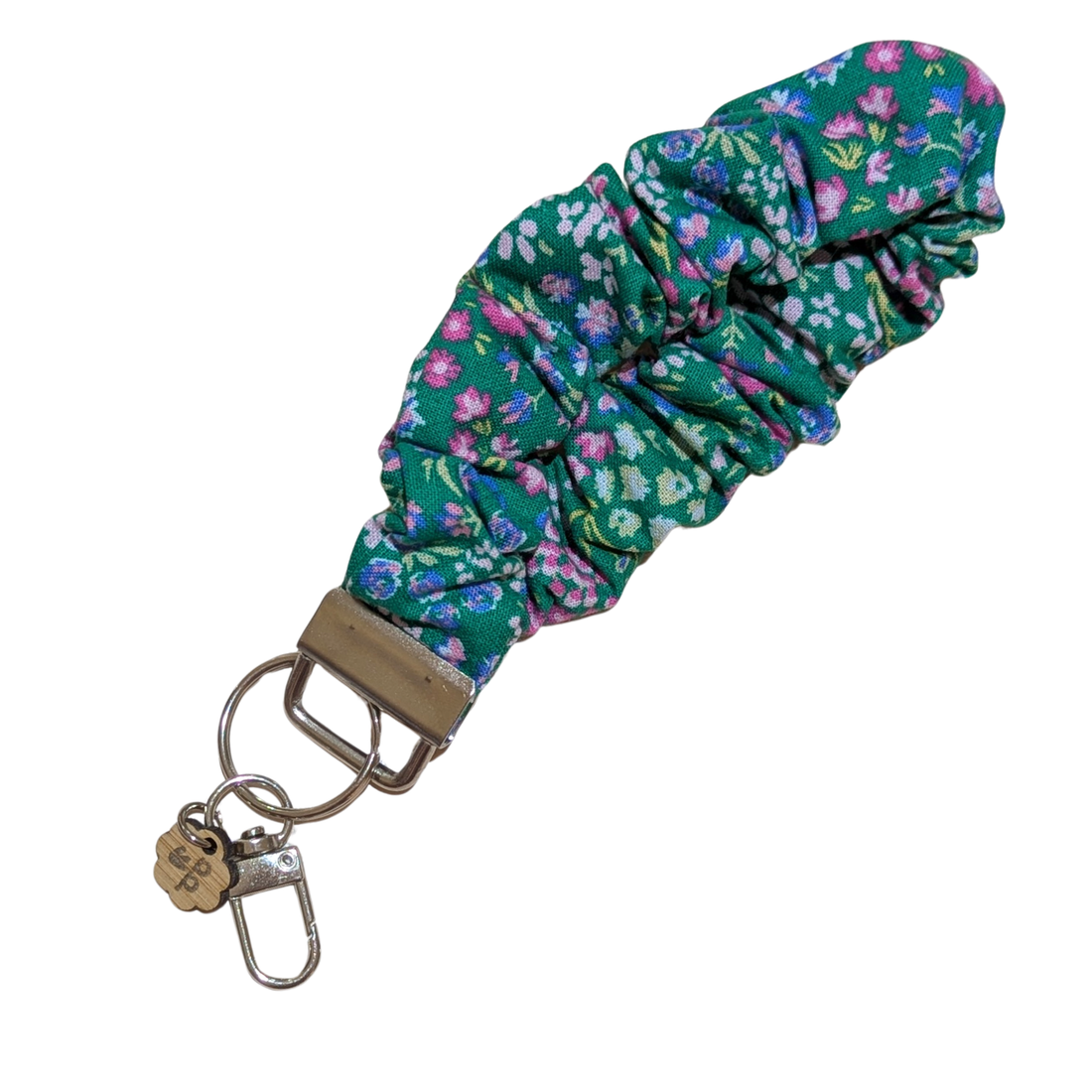 Handmade floral scrunchie wristlet with green fabric and pink-purple flowers — soft, stretchy keychain for everyday use.