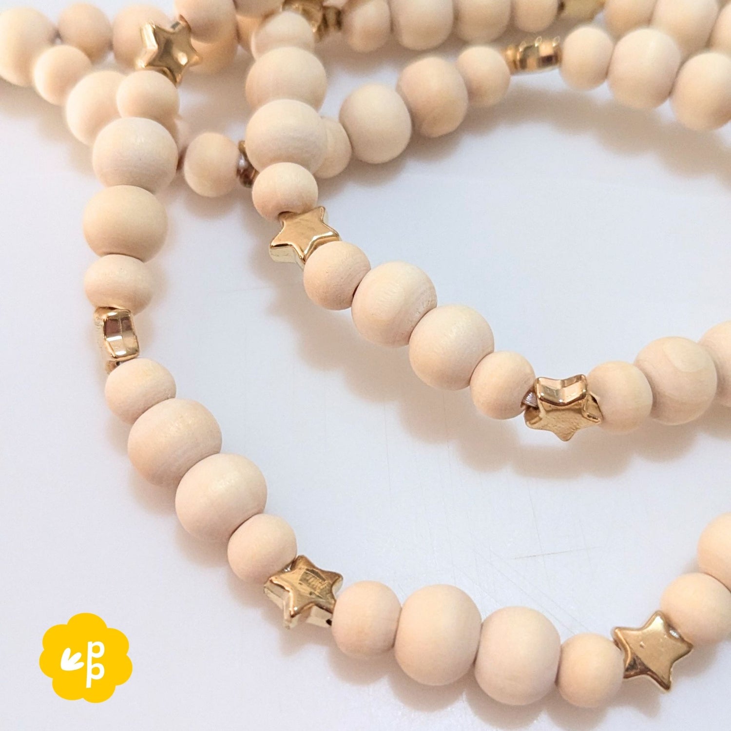 Close up of wooden bead lanyard with metallic gold star beads and spacer details
