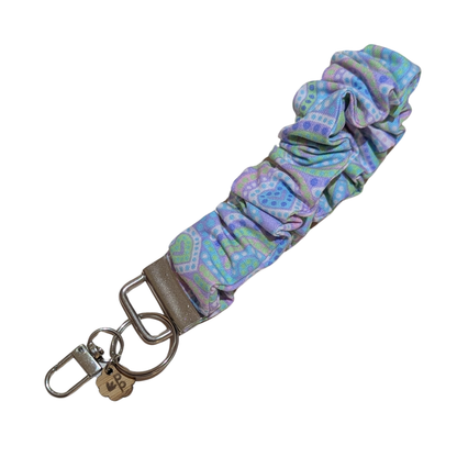 Handmade scrunchie wristlet keychain in purple and green patterned fabric — perfect for teachers or on-the-go moms.