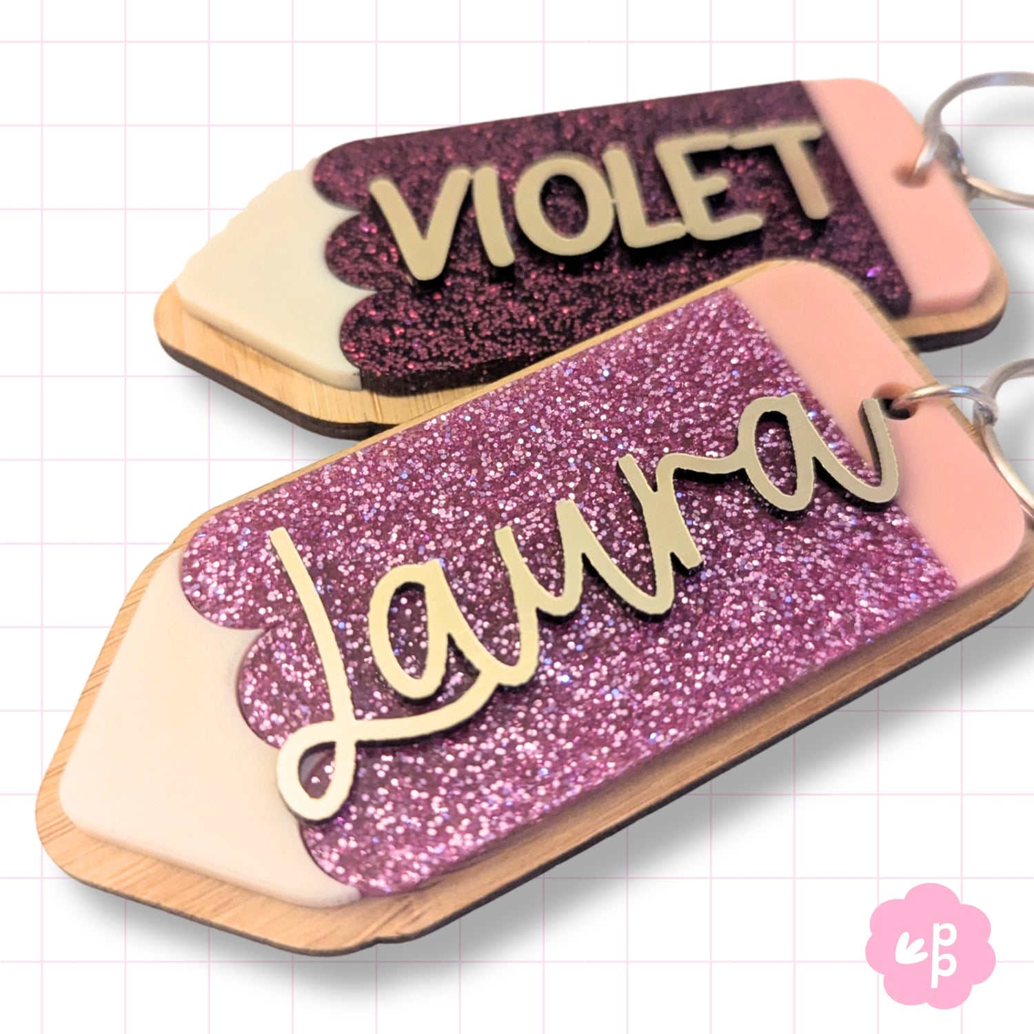Layered acrylic personalised name keyrings with glitter finish and raised lettering detail in purple and pink