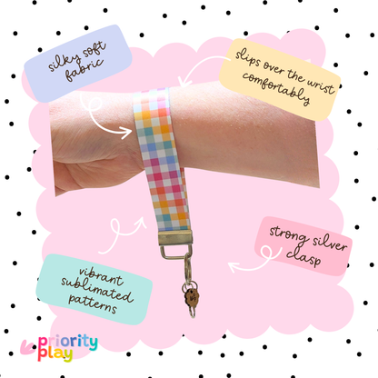 Pastel gingham fabric wristlet keychain shown on wrist with strong silver clasp, soft handmade key fob for teachers.