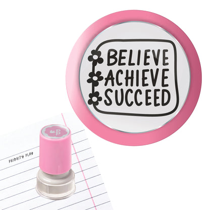 Pink teacher stamp showing the words “Believe Achieve Succeed” inside a notebook-style border with flower icons.