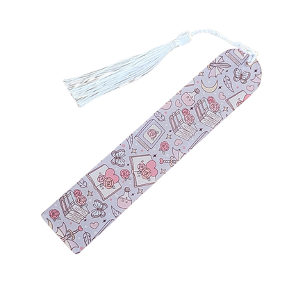 Handmade acrylic bookmark with pink roses, books, and hearts in a romantic theme, finished with white tassel.