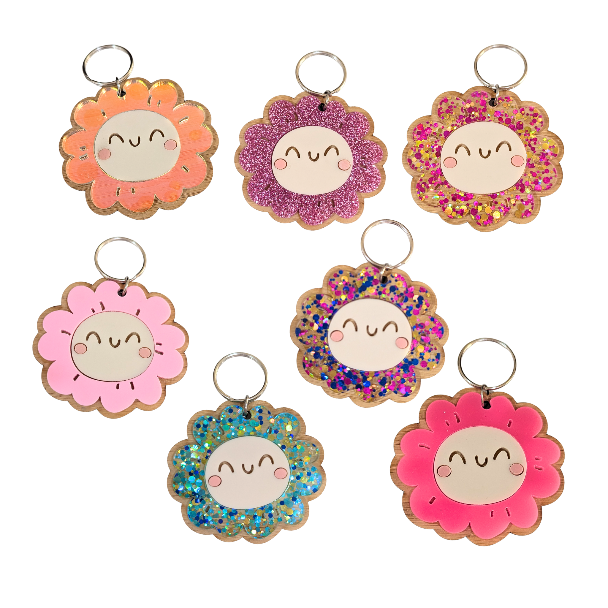 Cute smiley flower keyrings in bright and glitter colors including pink, blue, orange, and gold, with bamboo backing — Priority Play collection.