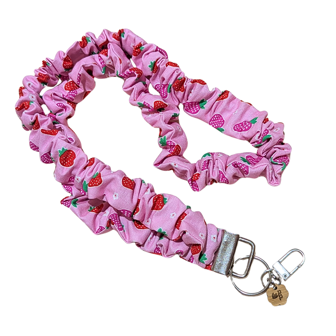 Pink scrunchie with strawberry pattern and keychain on a white background