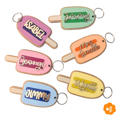 Personalised teacher name keychains in popsicle shape with pastel acrylic colours and bamboo backing, featuring custom names in gold lettering